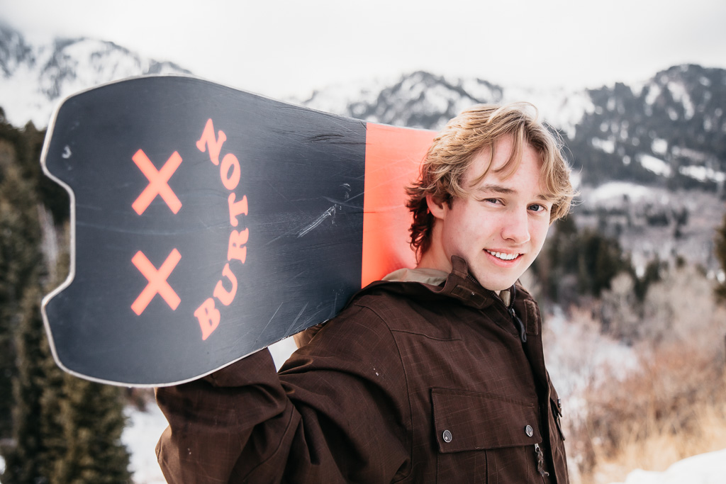 snowboarder holding snowboard on his shoulders 