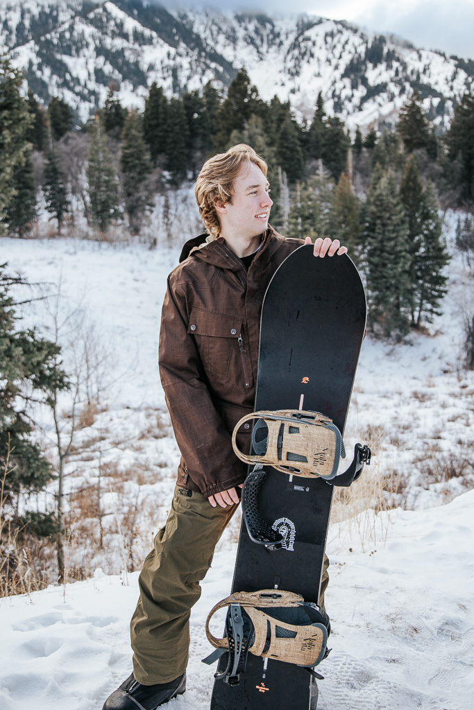 snowboarder holding snowboarding looking outward 